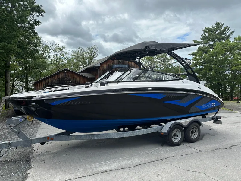 Slide: The Image of 2016 Yamaha Boats 242X E-Series on trailer, parked outdoors under cloudy sky. - 16
