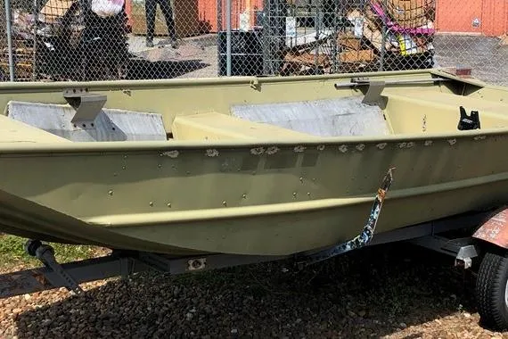 The Image of 1996 Lowe L1648 Big Jon boat on trailer, parked outdoors near a chain-link fence. - 2