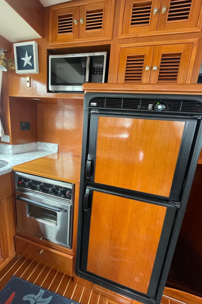 Slide: The Image of 2006 North Pacific 42 yacht kitchen with wood cabinetry, fridge, oven, and microwave. - 11