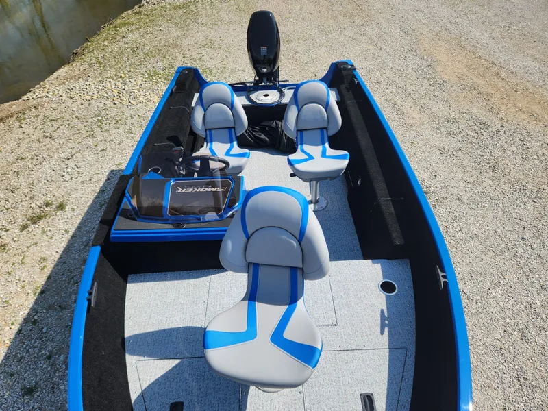 Slide: The Image of 2025 Smoker Craft Lazer 161 boat with blue and gray seating, docked on gravel. - 15