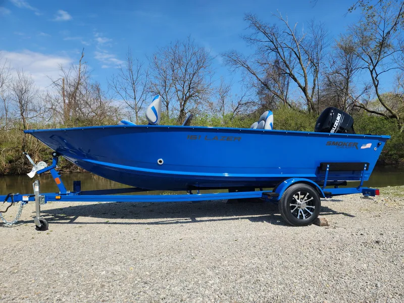 Slide: The Image of 2025 Smoker Craft Lazer 161 boat on trailer, vibrant blue, parked outdoors. - 16