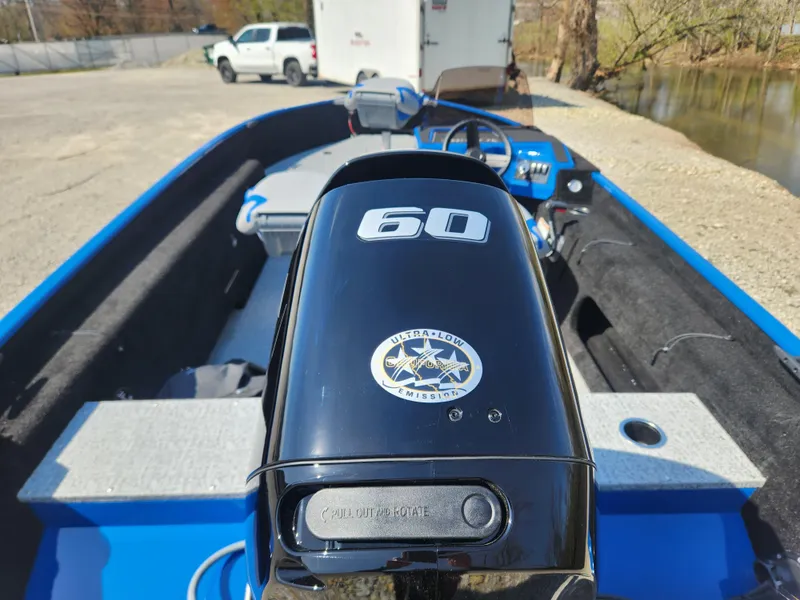 Slide: The Image of 2025 Smoker Craft Lazer 161 boat with 60 HP engine, parked near a river. - 4