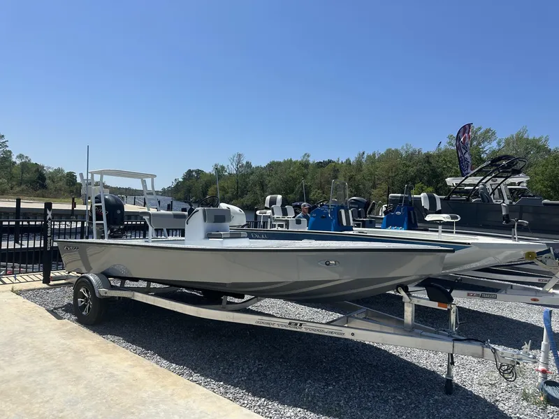Slide: The Image of 2025 Xpress Skiff 185 boat on trailer, displayed outdoors under clear blue sky. - 1