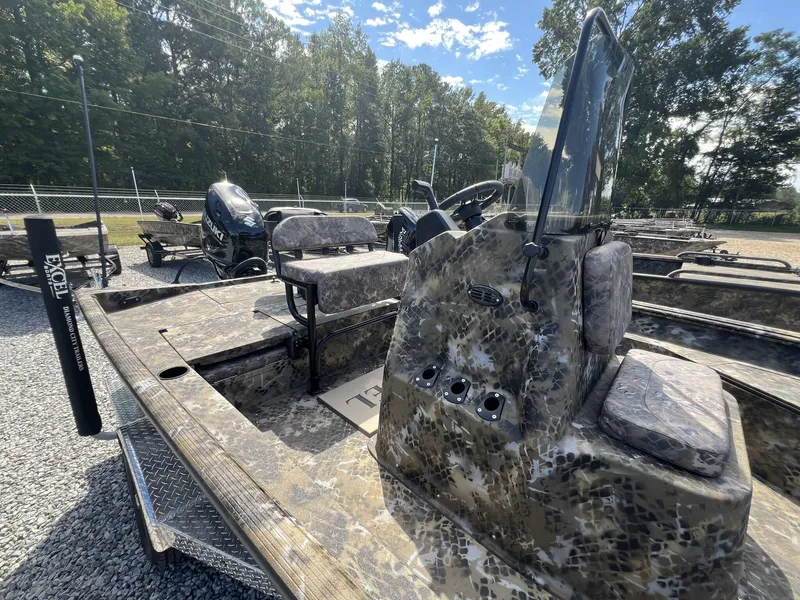 Slide: The Image of 2025 Excel Bay Pro 203 Elite boat with camouflage design, parked outdoors on gravel. - 4