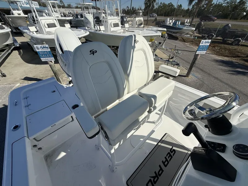Slide: The Image of 2025 Sea Pro 230 Bay boat interior with steering wheel and seating, displayed at a dealership. - 10