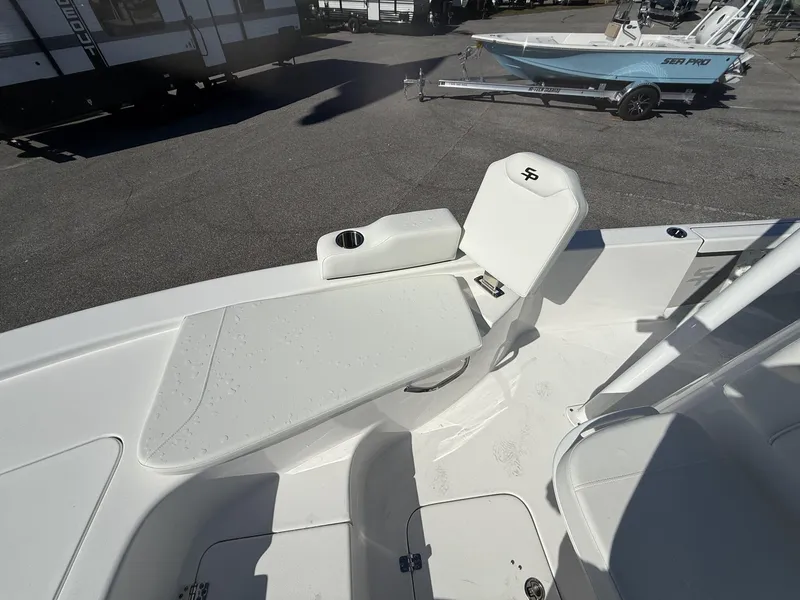 Slide: The Image of 2025 Sea Pro 230 Bay boat interior with seating and cup holder, parked outdoors. - 7