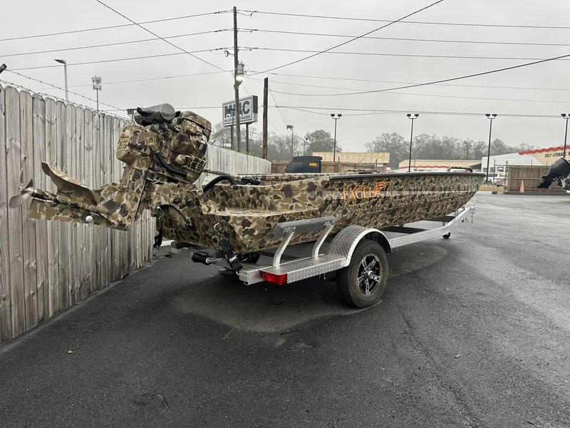 Slide: The Image of 2025 Excel Shallow Water F4 boat with camo paint on a trailer in a parking lot. - 2