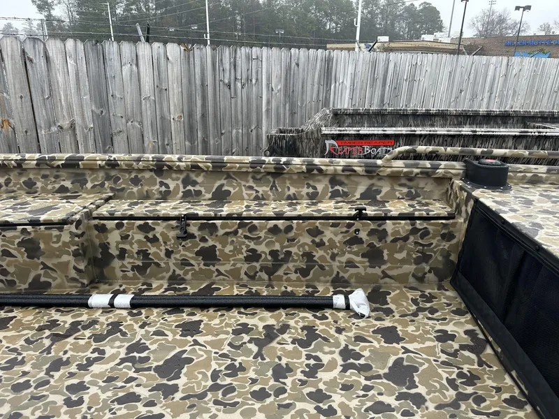 Slide: The Image of 2025 Excel Shallow Water F4 boat with camouflage paint, parked outdoors. - 5