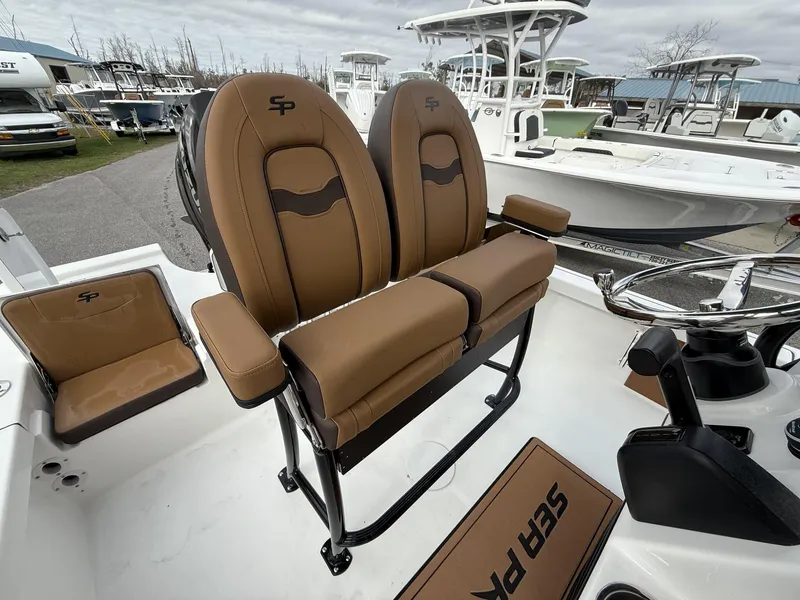 Slide: The Image of 2025 Sea Pro 230 Bay boat with tan seating and steering wheel, docked outdoors. - 4