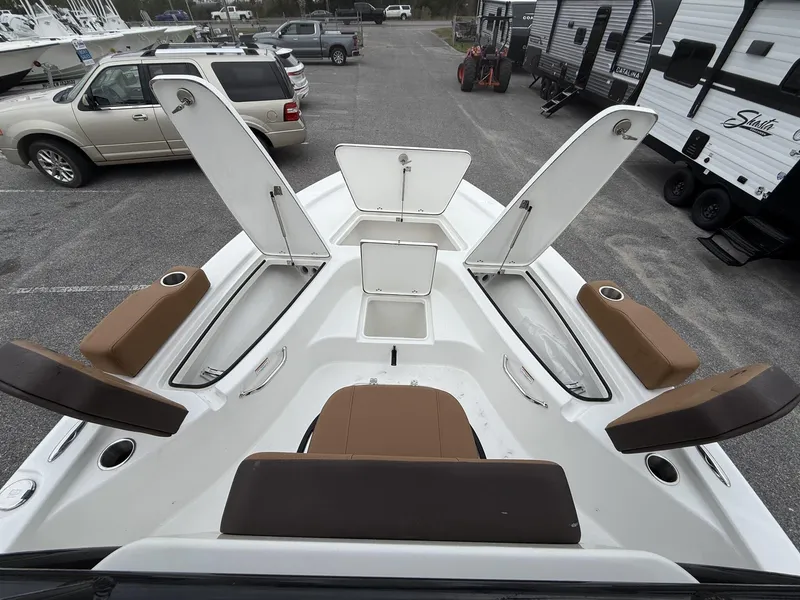 Slide: The Image of 2025 Sea Pro 230 Bay boat with open storage compartments and seating in a parking lot. - 8