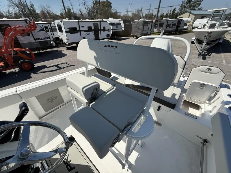 Slide: The Image of 2025 Sea Pro 225FLX SANDBAR boat interior with seating and steering wheel, parked near RVs. - 14