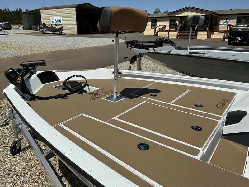 Slide: The Image of 2025 Xpress Hyper-Lift Series H18 bass boat with tan deck, parked outdoors. - 2