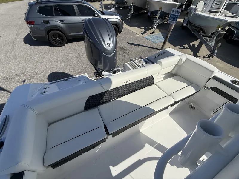 Slide: The Image of 2025 Tidewater 220 LXF boat interior with seating and motor, parked near vehicles. - 12