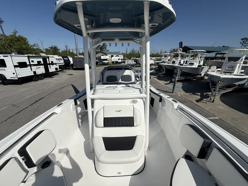 Slide: The Image of 2025 Tidewater 220 LXF boat interior with seating and T-top, displayed in a marina. - 6