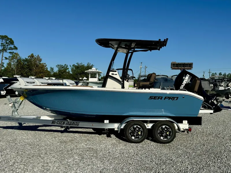 Slide: The Image of 2025 Sea Pro 202 boat on trailer, blue hull, Suzuki outboard, parked outdoors. - 2