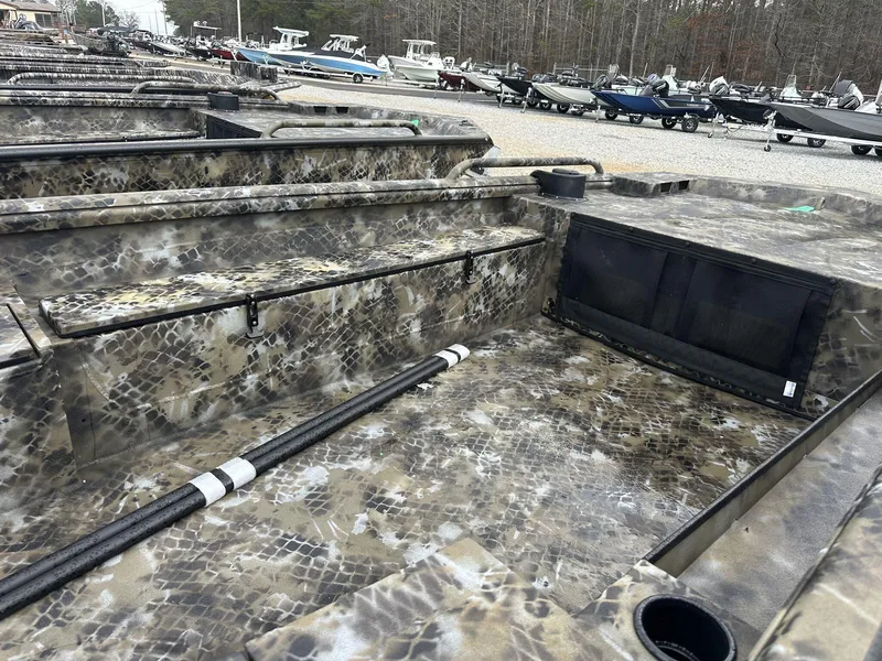 Slide: The Image of 2025 Excel Shallow Water F4 boat with camouflage design, parked among other boats. - 5