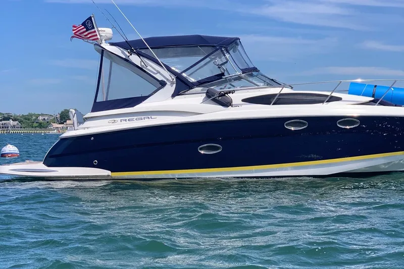 Slide: The Image of 2006 Regal 3360 Window Express boat on water, American flag, clear sky. - 0