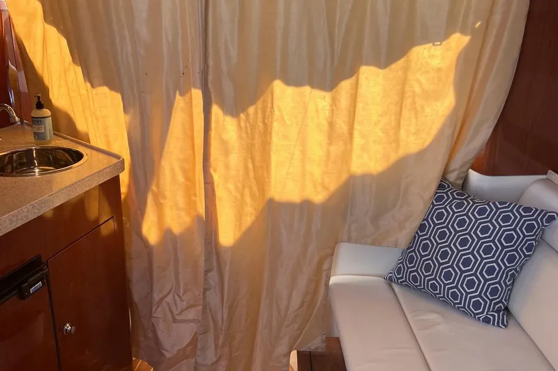 Slide: The Image of Interior of 2006 Regal 3360 Window Express with curtain, sink, and cushioned seating. - 21