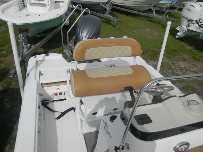 Slide: The Image of 2025 NauticStar 214 Shallow Bay boat interior with tan seating and steering console. - 2