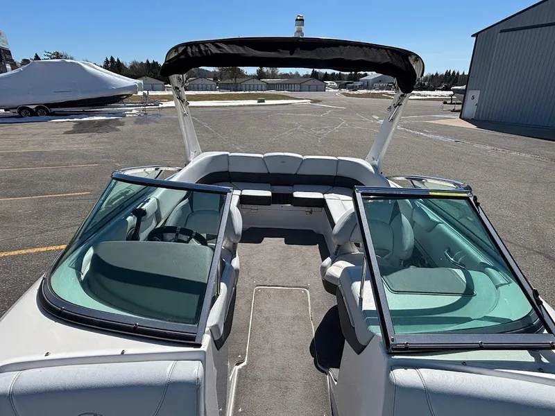 Slide: The Image of 2013 Regal 2300 Bowrider boat with open seating and canopy, parked on asphalt. - 25