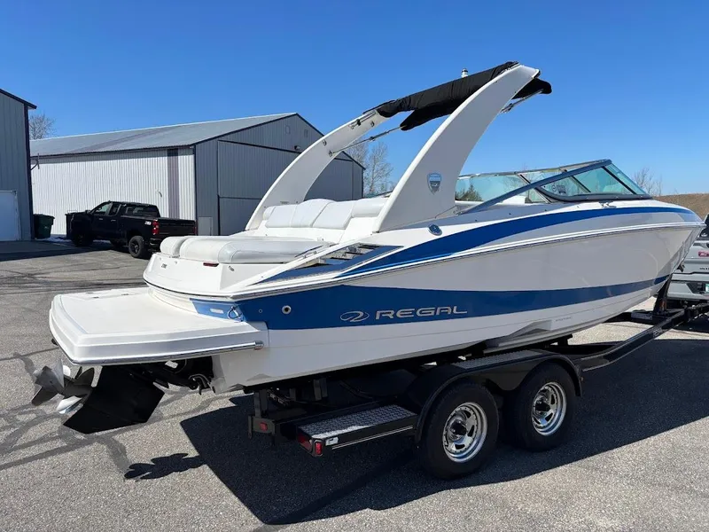 Slide: The Image of 2013 Regal 2300 Bowrider boat on trailer, parked outdoors near a building. - 6