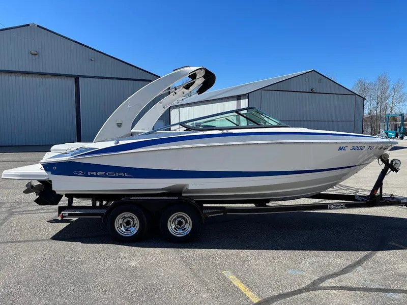 Slide: The Image of 2013 Regal 2300 Bowrider boat on trailer, parked near industrial buildings. - 7