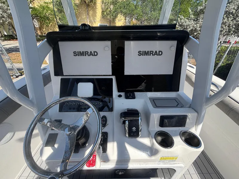 Slide: The Image of 2022 Sea Pro 239 Center Console boat dashboard with dual Simrad displays and steering wheel. - 14