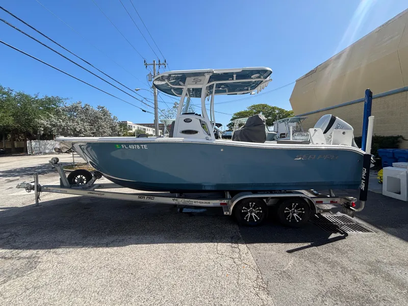 Slide: The Image of 2022 Sea Pro 239 Center Console boat on trailer, parked outdoors under clear sky. - 2