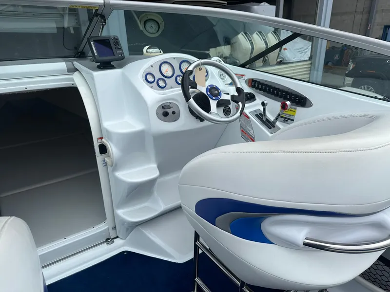 Slide: The Image of 2005 Baja 245 Performance boat interior with white and blue seating, steering wheel, and dashboard controls. - 5