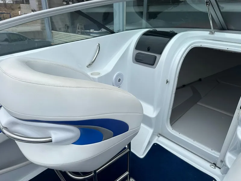Slide: The Image of Interior of a 2005 Baja 245 Performance boat, featuring a white and blue seat and cabin entrance. - 6