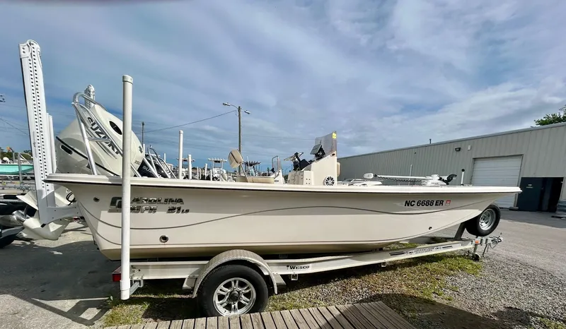 Slide: The Image of 2021 Carolina Skiff 21 LS boat on trailer, parked outdoors under cloudy sky. - 0