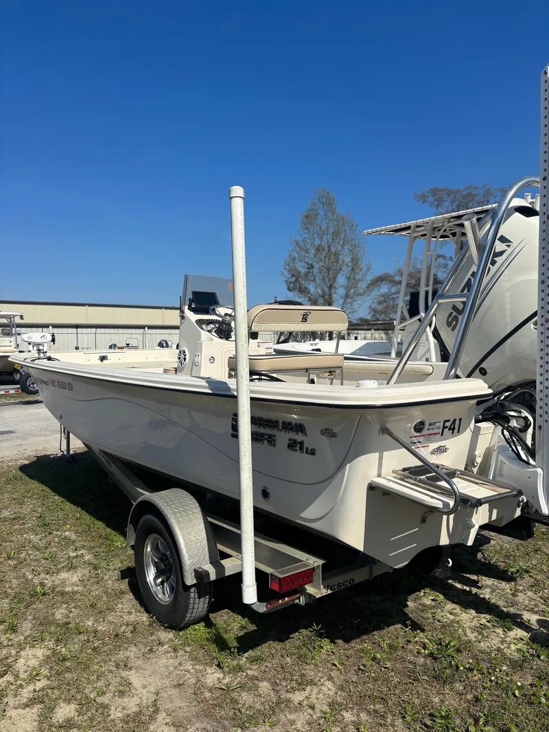 Slide: The Image of 2021 Carolina Skiff 21 LS boat on trailer, parked outdoors under clear blue sky. - 3