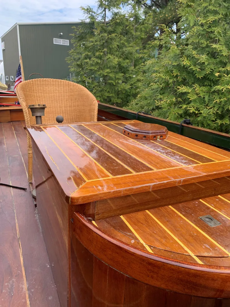 Slide: The Image of Classic 1990 English Launch boat with wooden deck and wicker chair, surrounded by greenery. - 28