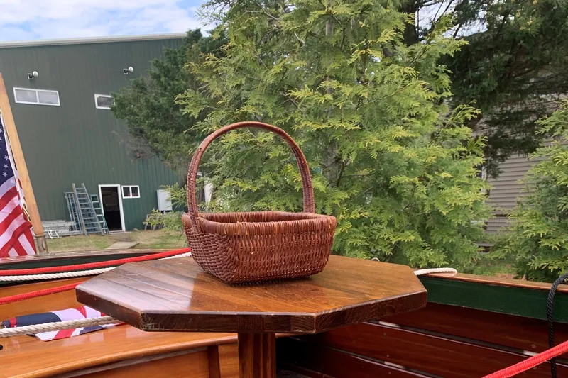 Slide: The Image of Wicker basket on wooden table aboard 1990 Classic English Launch, with trees and building in background. - 36