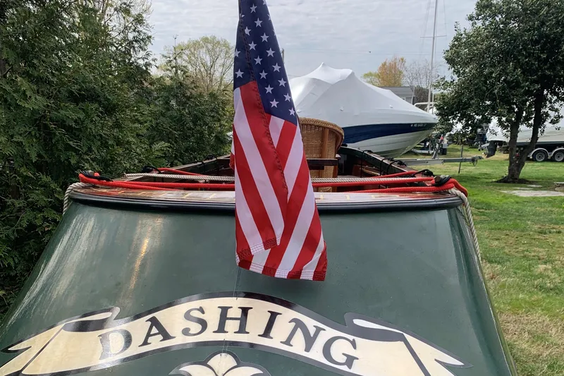 Slide: The Image of Classic 1990 English Launch boat with American flag, named "Dashing," docked outdoors. - 37