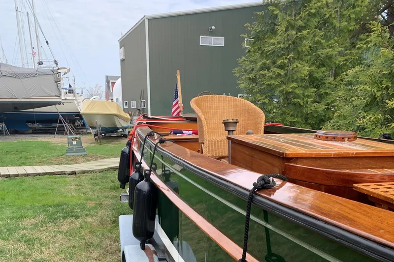 Slide: The Image of Classic English Launch boat from 1990 with wooden deck, docked near a green building. - 41