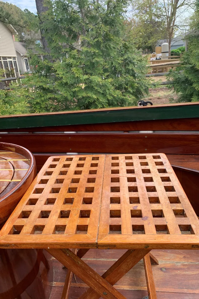 Slide: The Image of Wooden lattice table on a 1990 Classic English Launch boat, surrounded by greenery. - 43