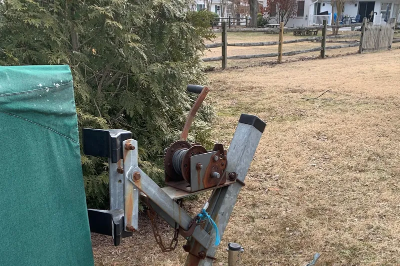 Slide: The Image of Trailer hitch with winch in a grassy yard, near a Classic English Launch, 1990 model. - 47