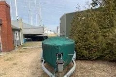 Slide: The Image of Covered 1990 Classic English Launch boat on trailer, parked outdoors near buildings and trees. - 48