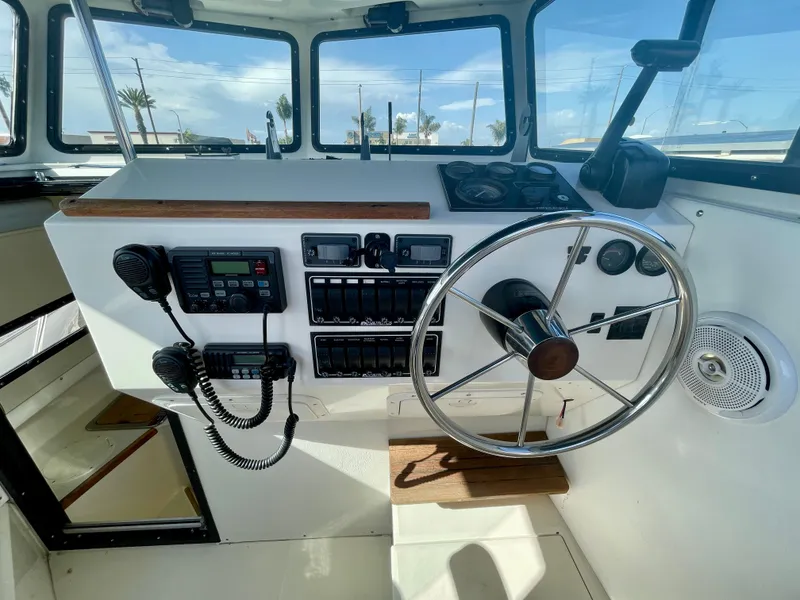 Slide: The Image of 1993 Skipjack 263 Fisherman boat cockpit with steering wheel and control panel. - 17