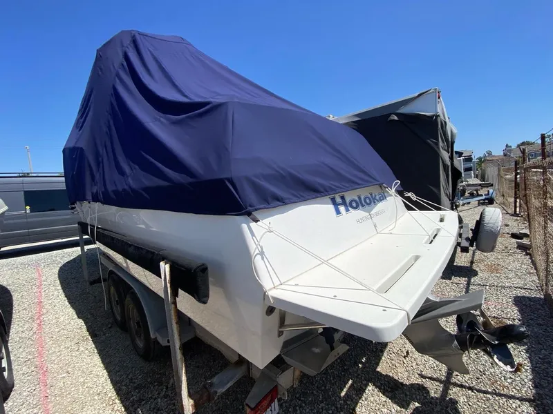 Slide: The Image of 1993 Skipjack 263 Fisherman boat with blue cover, parked on a trailer. - 2