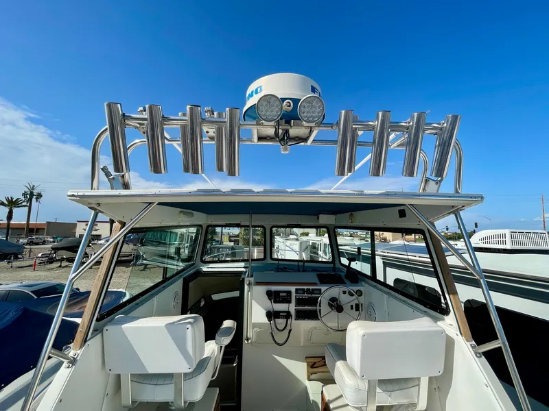 Slide: The Image of 1993 Skipjack 263 Fisherman boat interior with steering wheel and seating under clear blue sky. - 20