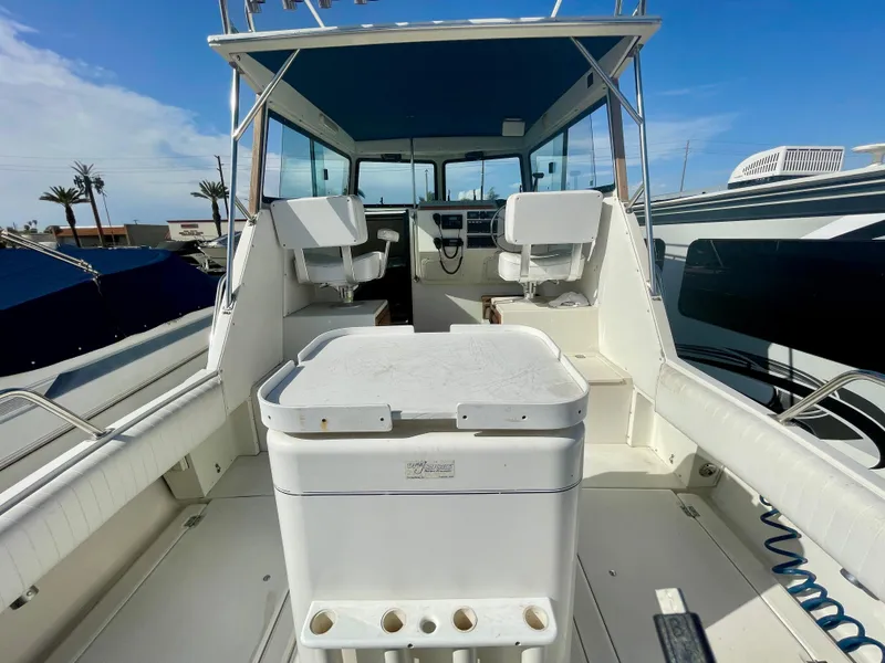 Slide: The Image of 1993 Skipjack 263 Fisherman boat interior with seating and helm, under clear blue sky. - 22