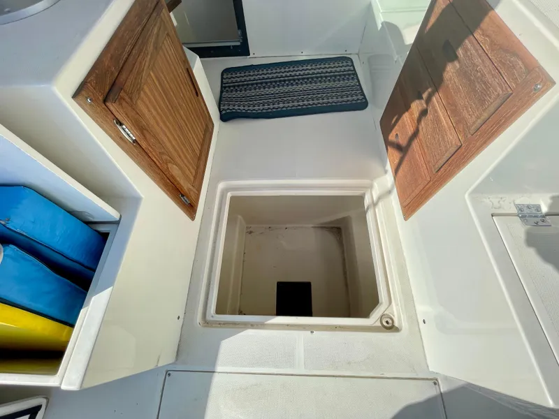 Slide: The Image of Open storage compartment on 1993 Skipjack 263 Fisherman boat with wooden doors and colorful cushions. - 24