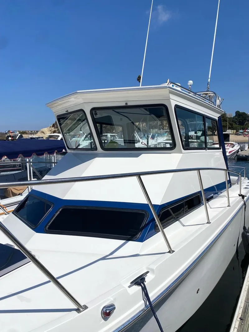 Slide: The Image of 1993 Skipjack 263 Fisherman boat docked, featuring a sleek white cabin and blue accents. - 3