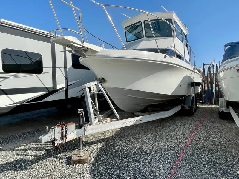 Slide: The Image of 1993 Skipjack 263 Fisherman boat on trailer, parked on gravel, beside an RV. - 7