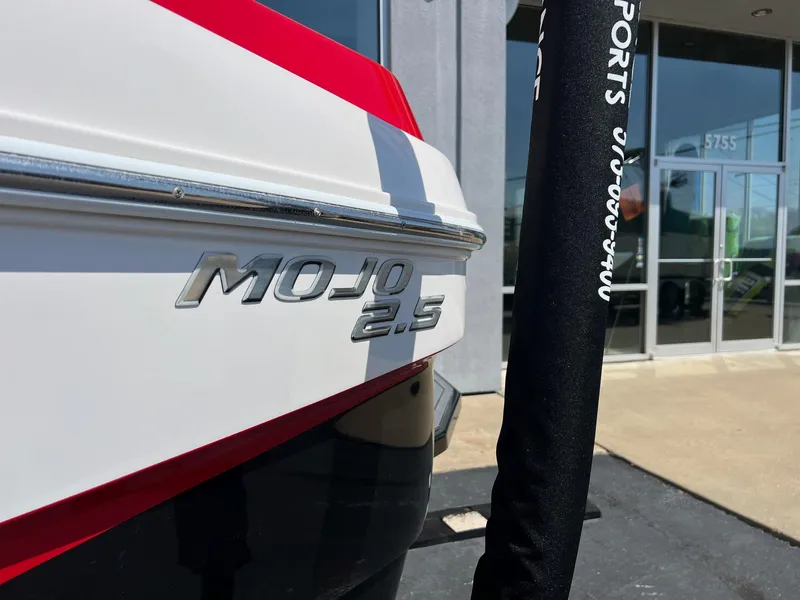 Slide: The Image of 2013 Moomba Mojo 2.5 boat rear view with logo, parked near a building. - 3