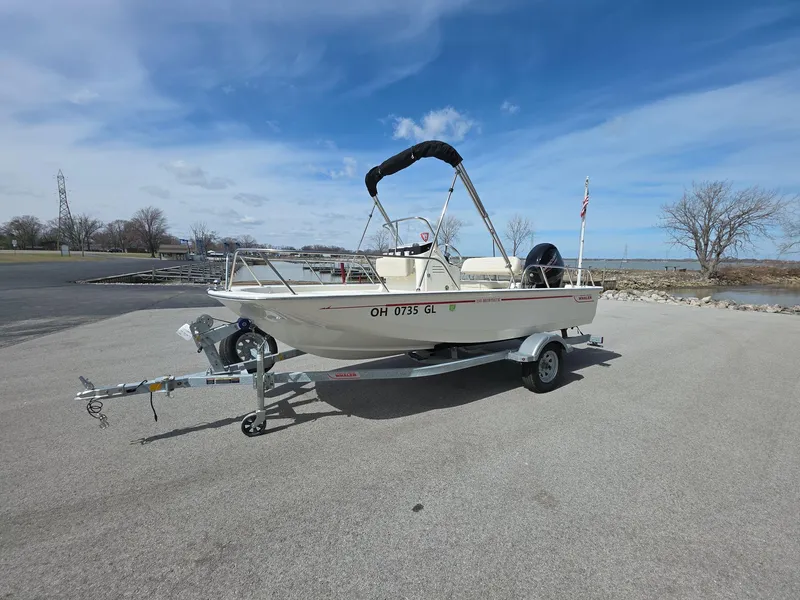 The Image of 2024 Boston Whaler 150 Montauk boat on trailer, parked outdoors under a clear sky. - 0