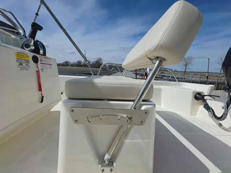 Slide: The Image of 2024 Boston Whaler 150 Montauk boat interior with cushioned seating and control panel. - 14