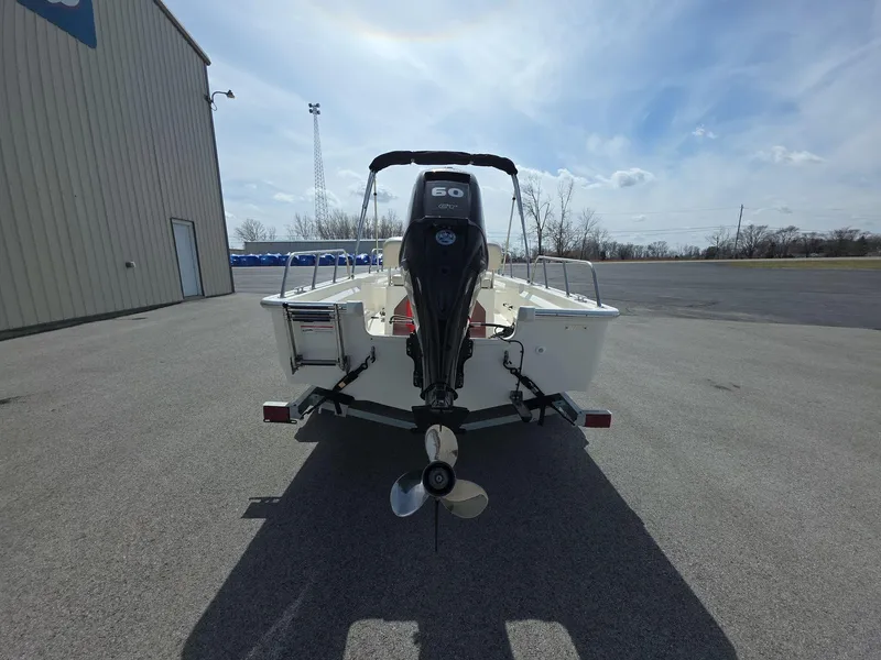 Slide: The Image of 2024 Boston Whaler 150 Montauk boat with outboard motor, parked outdoors. - 4